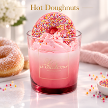 A pink frosted hot doughnut candle in a clear glass jar with a gold LV Collection logo, topped with a sprinkle-covered doughnut. The scene is styled with powdered doughnuts, sprinkles, and a pink cloth on a bright white surface, with the words 'Hot Doughnuts' at the top.