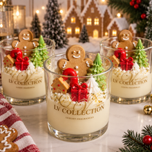Three glass jar candles from LV Collection decorated with whipped cream, gingerbread cookies, green trees, and red gift boxes, arranged on a marble surface with holiday decorations in the background.
